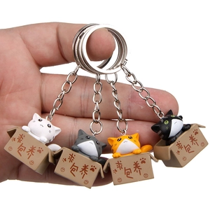 Detail of four colorful 3D cartoon cat keychains in boxes held by hand