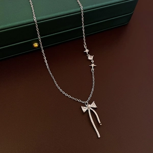 Detailed view of silver bow necklace with pink zircon tassels on dark jewelry box