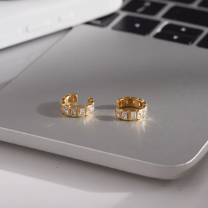 Minimalist gold-plated ear cuff with rectangular zircon stones on a laptop surface