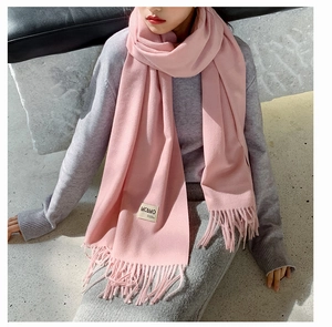 Detail of pink cashmere blend scarf featuring soft tassel edges and stitched brand label