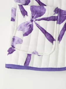 Detail of a diamond quilted jacket pocket with purple bow print and contrast piping