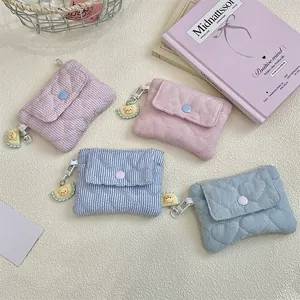 Close-up of quilted mini wallets in four pastel colors with button snaps and metal hooks