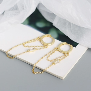 Macro shot of gold tassel earrings featuring double chains and sparkling zircon pendants