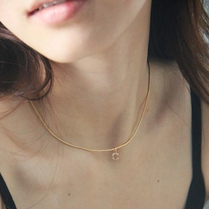 Close-up of golden snake chain necklace with sparkling letter C pendant on a model