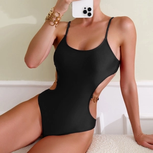 Detail of black monokini swimsuit featuring cut-out waist and gold chain link accents