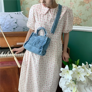 Retro blue washed denim crossbody bag held by a model in a nostalgic vintage setting