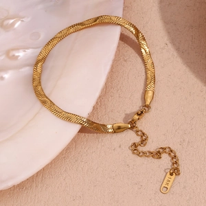 Detailed macro view of gold-plated herringbone bracelet with 18K hallmark tag