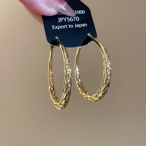 Detailed close-up of golden twist texture hoop earrings with polished metal finish