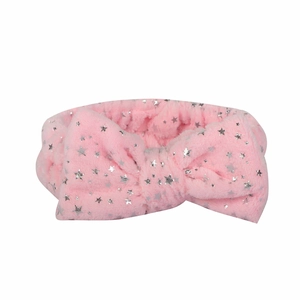 Detail of pink plush headband with silver stars and a large bow for skincare