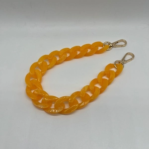 Macro shot of vibrant orange acrylic chunky chain strap with gold metal lobster clasps