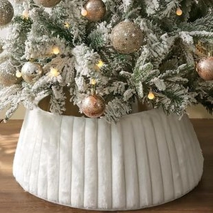 Close-up of a white plush Christmas tree skirt with vertical textured patterns and warm lights