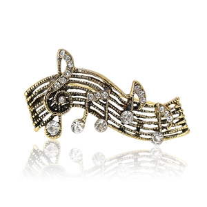 Vintage gold musical note brooch with sparkling crystals on white background