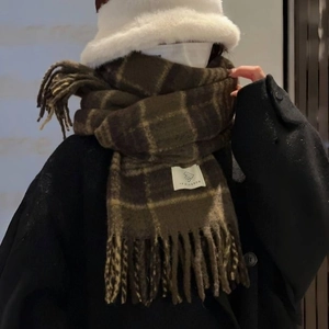 Detail view of brown plaid scarf with fringe and a beige textile label for vintage style