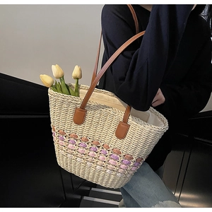 Close-up of colorful floral weave and brown leather straps on straw tote bag