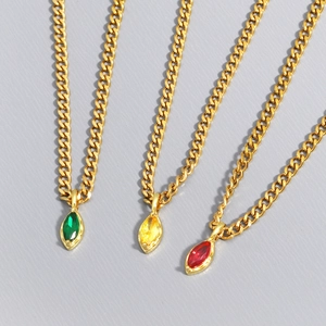 Detailed view of three gold cuban chains with green, yellow and red marquise-cut gems