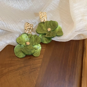 Detailed view of green resin flower earrings with gold hammered square metal studs