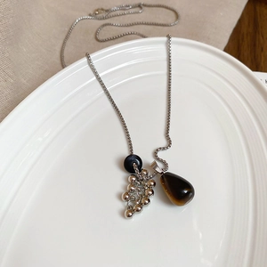 Detail of silver chain necklace with brown tiger eye stone and beaded tassel pendant