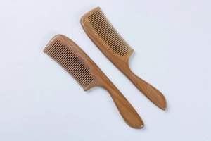 Detailed view of two natural sandalwood combs with round handles and fine teeth on white