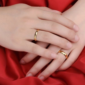 Close-up of highly polished gold titanium steel domed rings worn on hands
