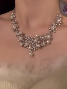 Close-up of floral silver necklace with pearls and diamonds on model neck
