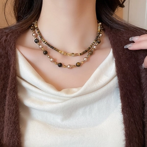 Macro view of double-layered pearl and tiger eye stone necklace on a model neckline