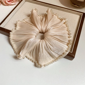 Détail du chouchou en satin champagne avec bordure élégante en perles de culture