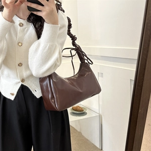 Deep brown glossy crescent underarm bag with trendy pleated strap in mirror selfie view