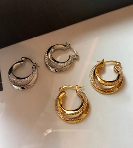 Close-up of double-layered geometric hoop earrings with crystals in gold and silver