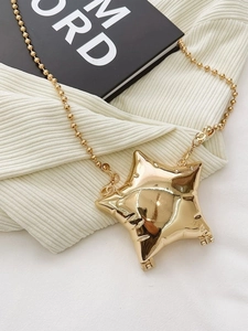 Shiny gold star shaped metal mini crossbody bag with chic ball chain strap on knit background