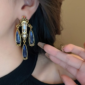 Vintage gold drop earrings with blue teardrop stones and rhinestones on model