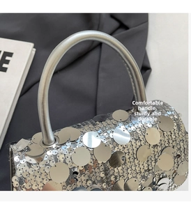 Detail of silver sequin square bag featuring a smooth metallic handle and shiny finish