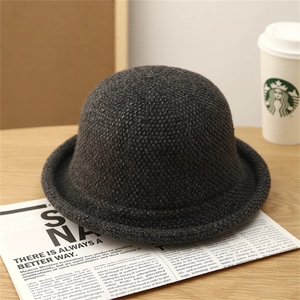 Detailed knit texture of dark gray dome bucket hat on vintage newspaper backdrop