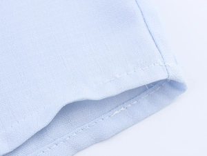 Macro detail of light blue fabric texture and double-stitched seam on French style blouse