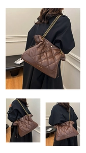 Detail view of brown quilted shoulder bag with gold chain strap and drawstring closure