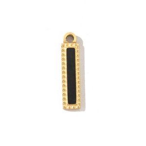 Macro shot of a vintage gold rectangle pendant with black enamel and dotted border detail