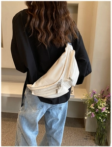 Rear view of a stylish white crossbody bag with multi-zipper pockets and wide strap