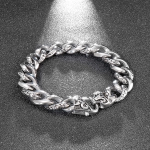 Macro detail of silver Cuban link bracelet with engraved snake skin pattern on the clasp