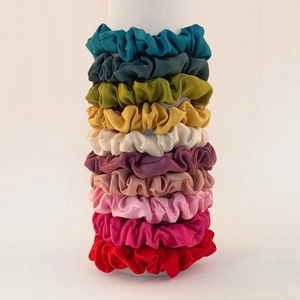 Macro view of 10 assorted satin silk scrunchies stacked neatly on a vertical display stand