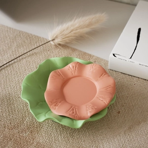 Dettaglio di un vassoio floreale con petali arancioni e base a foglia di loto verde