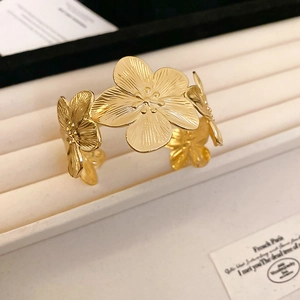 Detail of gold flower cuff bracelet showing brushed metal texture and floral design