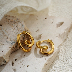 Close-up of 18K gold twisted interlocking hoop earrings on minimalist stone and lace