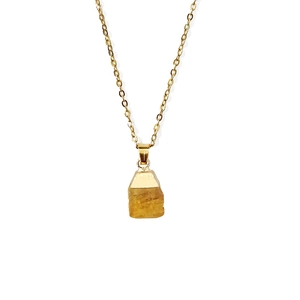 Macro view of a faceted yellow raw gemstone pendant with a delicate gold chain link