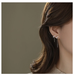 Detail showing elegant S925 sterling silver four-pointed star long tassel earrings on a model