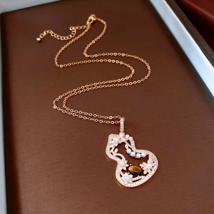 Detailed shot of rose gold necklace with hollow gourd pendant and tiger eye stone