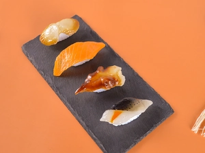 Modèles de sushis réalistes au saumon et aux pétoncles sur un plateau de pierre