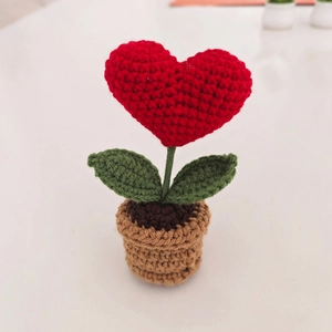 Handmade crochet red heart plant in brown pot decor on white desk background