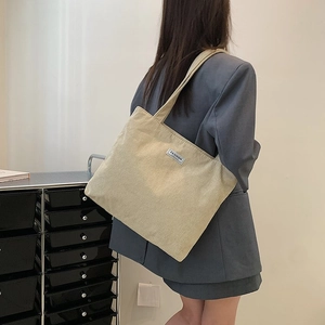 Close-up of beige corduroy tote bag texture showing fashion label and soft fabric