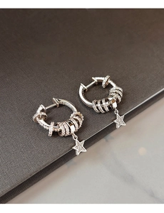 Detailed view of silver hoop earrings with zircon star pendant and pavé setting design