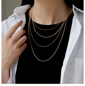 Close-up of a layered gold-plated stainless steel necklace worn over a white shirt