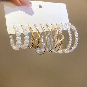 Close-up of golden pearl hoop earring set with various textures on a display card